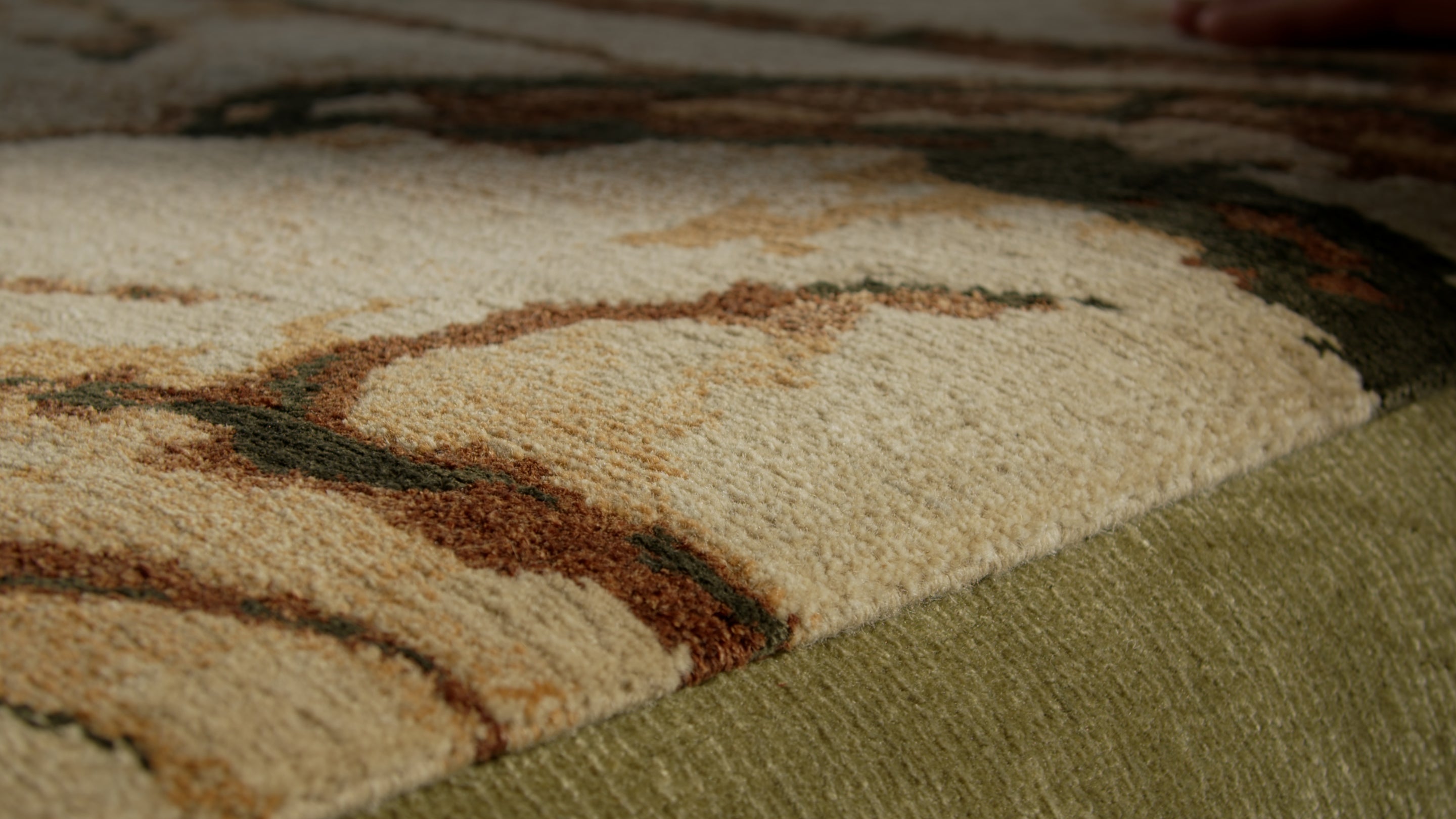 A hand carved rug in deep green and gold, close up