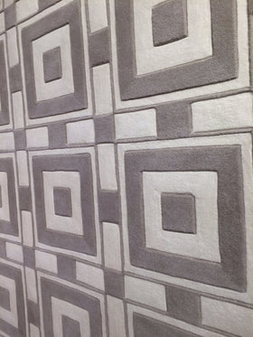 Gray and off-white geometric patterned rug with a raised, textured square frame design.