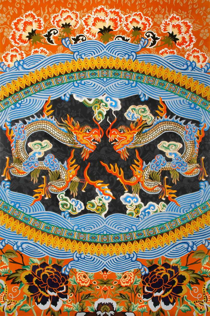A close-up of a colorful traditional textile or artwork featuring two dragons facing each other within a circular border, surrounded by blue waves, floral motifs, and orange background details.