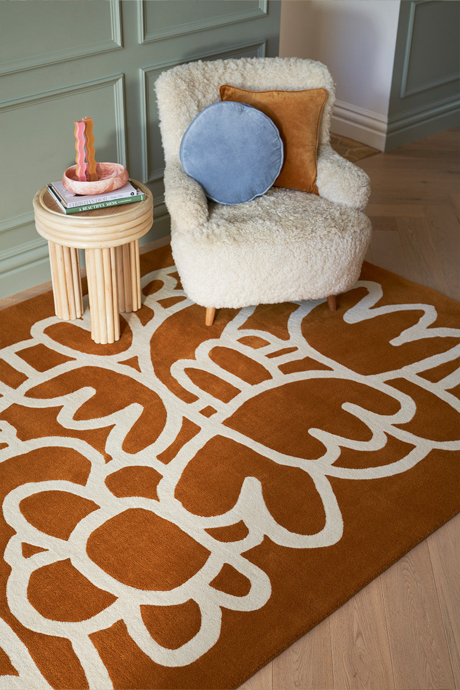 White fluffy armchair with decorative pillows on a patterned brown rug.