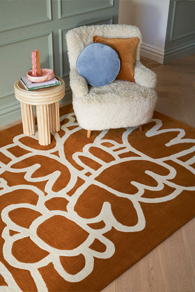 White fluffy armchair with decorative pillows on a patterned brown rug.