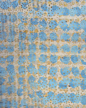 A close-up of a textured fabric or wallpaper pattern featuring light blue circular floral motifs, vertical dashed lines, and scattered gold glitter accents on a cream background.