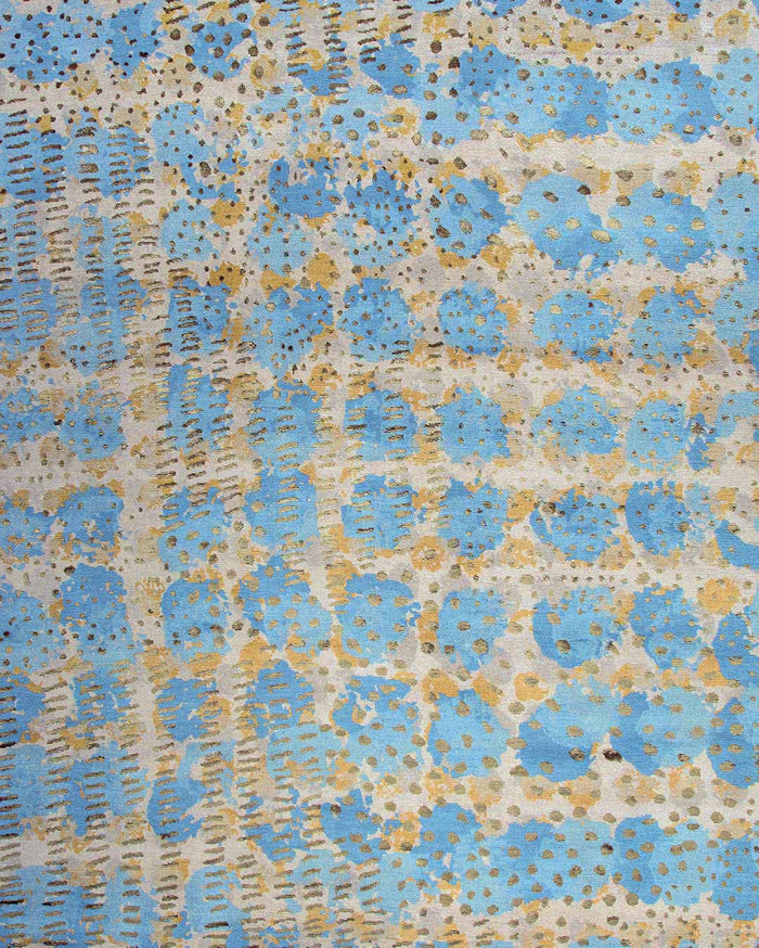 A close-up of a textured fabric or wallpaper pattern featuring light blue circular floral motifs, vertical dashed lines, and scattered gold glitter accents on a cream background.